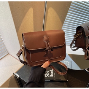 Close-up of brown vintage crossbody bag with white contrast stitching and horn buckle closure