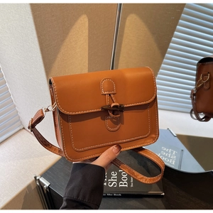 Close-up of brown vintage crossbody bag featuring toggle horn buckle and white stitching