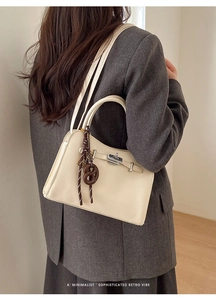 Detail of off-white lychee leather handbag with silver twist lock and pretzel charm