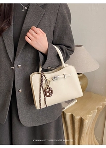 Chic beige leather handbag with twist-lock and retro pendant shown in a lifestyle scene