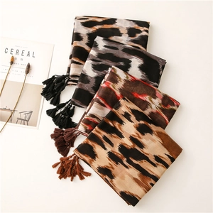Detalle de bufandas con estampado de leopardo, texturas suaves y bordes de flecos finos