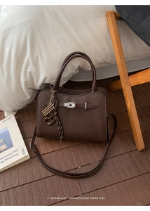 Detail of dark brown lychee texture leather handbag with silver clasp and charms