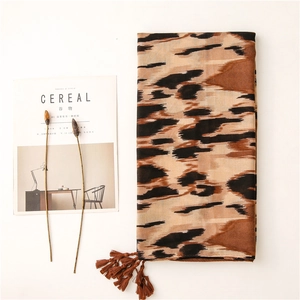 Detalle de bufanda con estampado de leopardo y flecos sobre un fondo minimalista