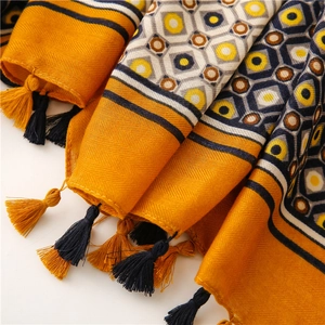 Close-up of yellow geometric scarf showing herringbone weave and tassel details