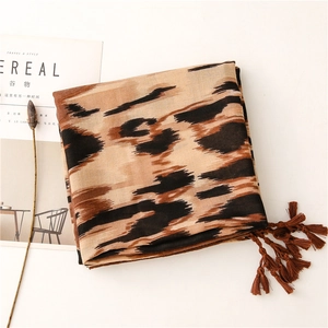 Detalle de bufanda con estampado de leopardo, flecos suaves y textura de tela fina
