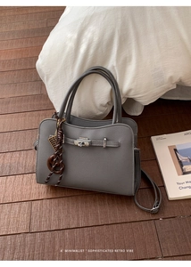 Detail of grey pebbled leather handbag with silver twist lock on wooden floor