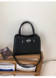 Macro detail of black litchi texture leather handbag with silver metallic twist lock closure