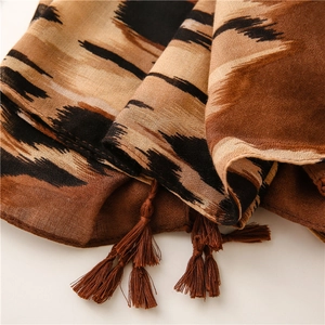 Detalle de la bufanda marrón con estampado de leopardo y pompones de flecos hechos a mano