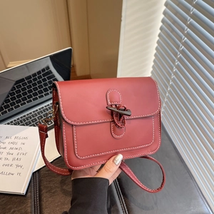 Red leather crossbody square bag with white stitching and decorative horn buckle