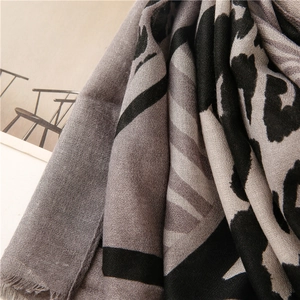 Détail d'une écharpe imprimé léopard avec texture douce et glands gris effilochés