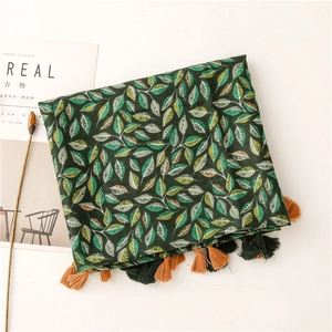 Détail de l'écharpe à motif feuilles vertes avec glands et texture en lin