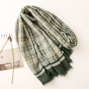 Close-up of olive green and beige plaid scarf with gold lurex stripes and soft fringe