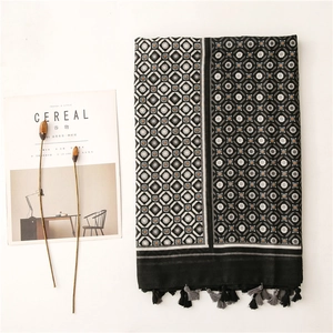 Detailed flat lay of geometric print scarf with fringes and minimalist earthy tones