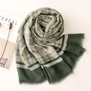 Detail of dark green woven scarf with gold metallic check pattern and soft fringe edges