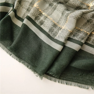 Detail of green and gray plaid scarf with gold embroidery and herringbone texture