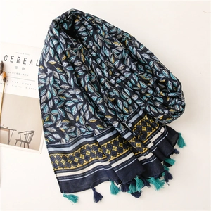 Détail d'une écharpe aspect lin avec motifs de feuilles bleues et pompons élégants