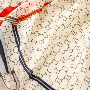 Detailed macro view of soft silk-like fabric with elegant monogram chain print textures