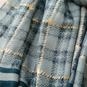 Detailed macro view of blue plaid scarf with shimmering gold thread and twill weave