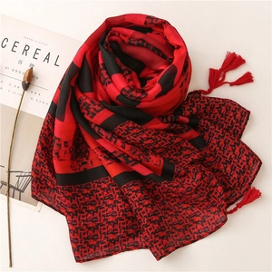 Vue détaillée de l'écharpe à carreaux rouge et noir avec franges et motifs floraux