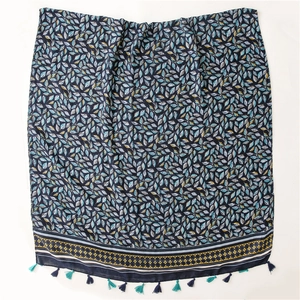 Détail d'une écharpe en coton bleu marine avec motif de feuilles et bordure à glands