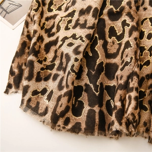 Detail of leopard print scarf featuring gold foil accents and natural fringed edges