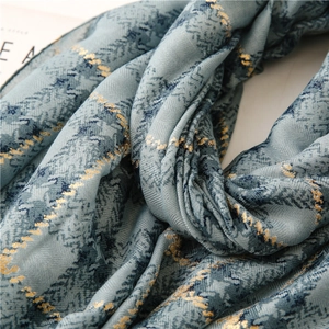 Detailed texture of blue linen scarf featuring gold foil grid patterns and soft fringe