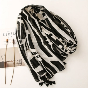 Detail of minimalist black and white geometric scarf featuring elegant black fringe tassels
