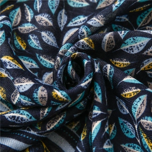 Vue rapprochée d'une écharpe bleu marine à motifs feuilles et bordure rayée en tissu