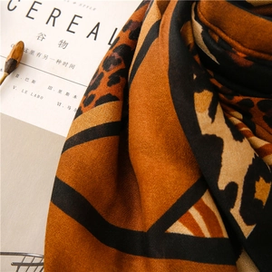 Détail d'une écharpe douce à imprimé léopard avec motifs géométriques orange et brun