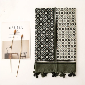 Detail of dark green scarf showing geometric patterns, fringe edges and cotton-linen texture