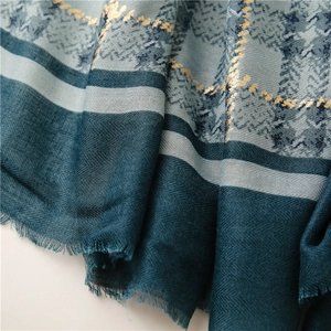 Detail of dark green and grey plaid scarf with metallic gold foil lines and fringe