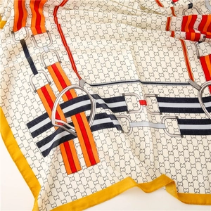 Detail of luxury silk scarf showing horsebit pattern and yellow borders on white fabric