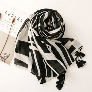 Detail of soft black and white geometric scarf with tassels on minimalist background