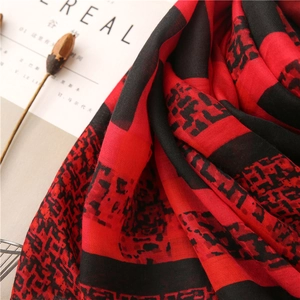 Gros plan d'une écharpe à carreaux rouge et noir en coton et lin avec des franges