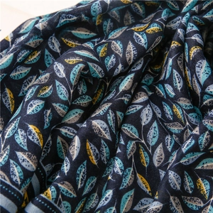 Détail du tissu bleu marine léger avec des motifs de feuilles bleu sarcelle et jaune