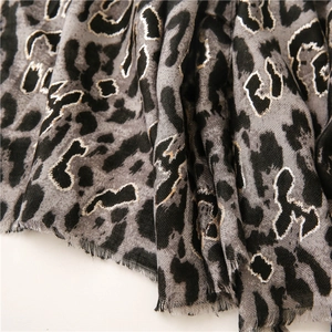 Detail of grey leopard scarf with gold metallic accents and frayed tassel edges