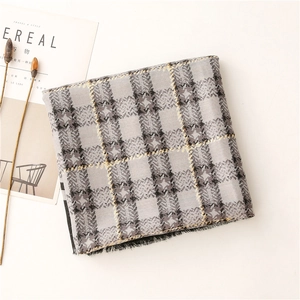Detail of grey and yellow checkered scarf with fringed edges on a minimalist table