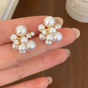 Detail view of pearl cluster earrings with white pearls and sparkling zircons in gold base