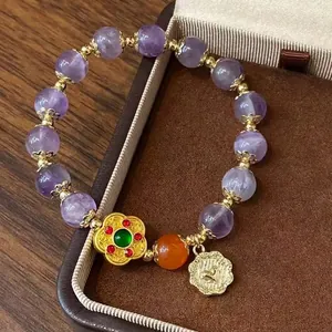 Détail d'un bracelet vintage avec perles en cristal violet et pendentif fleur dorée