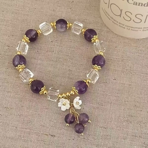 Détail d'un bracelet en perles d'améthyste violette avec pendentifs fleurs en nacre