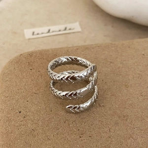 Détail d'une bague spirale argentée avec texture de plumes gravée et style vintage
