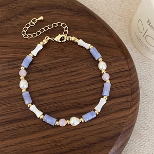 Macro detail of beaded necklace with freshwater pearls, purple stone, and bone charm