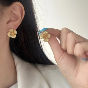 Elegant gold flower earrings with yellow resin petals on model showing minimalist style