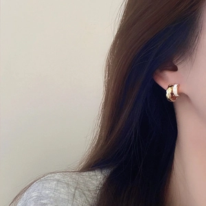 Chic gold quilted lattice and white enamel C-shape hoop earrings worn by a model