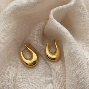 Boucles d'oreilles minimalistes en U dorées avec finition miroir polie sur lin