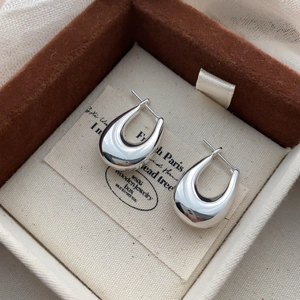 Détail macro de boucles d'oreilles argentées en U avec finition polie en boîte à bijoux
