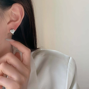 Boucles d'oreilles cœur en émail élégantes avec nœud argenté sur un mannequin