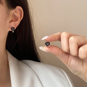 Boucles d'oreilles minimalistes en forme de cœur noir portées sur le lobe d'oreille