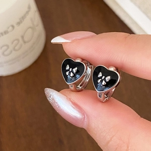 Gros plan de boucles d'oreilles cœur en argent avec émail noir et petit nœud