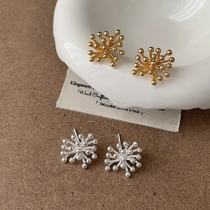 Elegant gold and silver firework stud earrings displayed on a minimalist ceramic tray